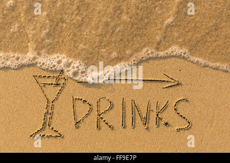 Word Drinks and arrow drawn on the sand of a beach with the soft wave. Stock Photo