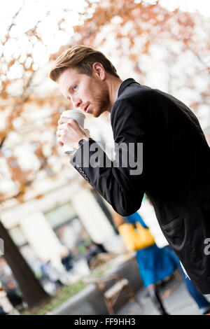 Young man drinking coffee to go on street Stock Photo