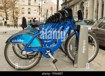A row of blue Citi Bike bicycles lined up on the sidewalk in the docking station outside City Hall in New York City Stock Photo