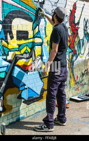 Street art in Shoreditch. Urban artist drawing graffiti on a wall in Shoreditch. Stock Photo