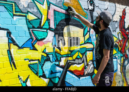 Street art in Shoreditch. Urban artist drawing graffiti on a wall in Shoreditch. Stock Photo
