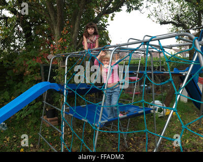 Two Girls Sisters On Climbing Frame In Garden England Stock Photo