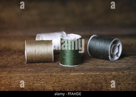 Set of Four Green and Khaki Sewing Spools on Wood Background Stock Photo