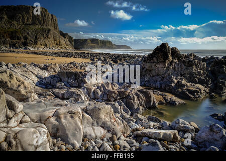 the beach and cliffs at bracelet bay, wales ,rockpools with sealife and fluffy white clouds Stock Photo