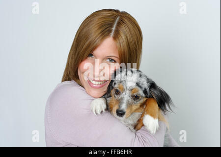Young woman holding young dog, Australian Shepherd Stock Photo