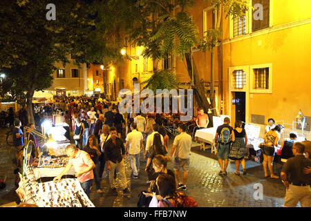 A cobblestone street with cafes and craft sellers in the Trastevere district of Rome at night. Stock Photo