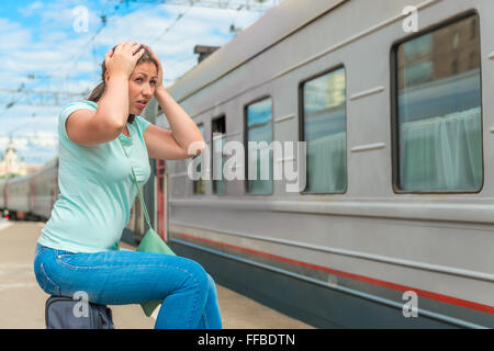 emotional woman looks at the departing train on which she was late Stock Photo