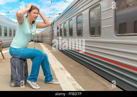 frustrated woman looking at the passing train on which she was late Stock Photo