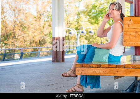 young and beautiful woman talks on the phone waiting for the train Stock Photo