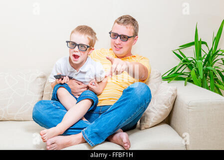 father and son in 3D glasses watching TV on the couch Stock Photo