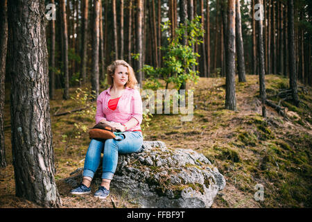 Beautiful Plus Size Young Woman In Shirt Sitting on Stone inSummer Forest Stock Photo