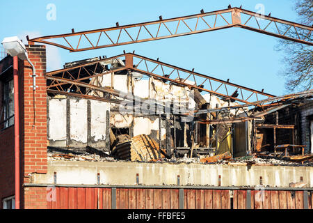 A small industrial building has burnt down. The roof is gone and some of the metal roof beams has been bent by the heat. Stock Photo