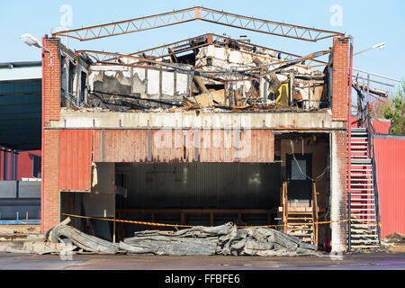 A small industrial building has burnt down. The roof is gone and some of the metal roof beams has been bent by the heat. Stock Photo