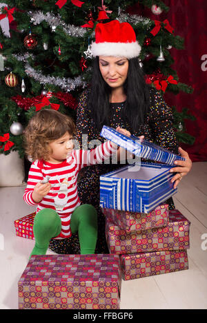 Mother and toddler son opening Christmas presents in their home