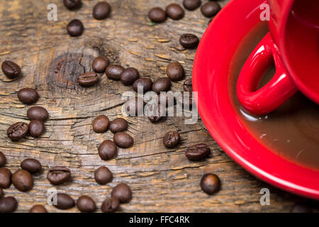 Coffee cup with spilled coffee and coffee beans on table Stock Photo