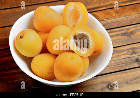 Bowl with apricots fruit on wooden table Stock Photo