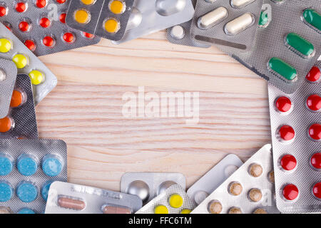 Pills and capsules in aluminum container on wooden table Stock Photo