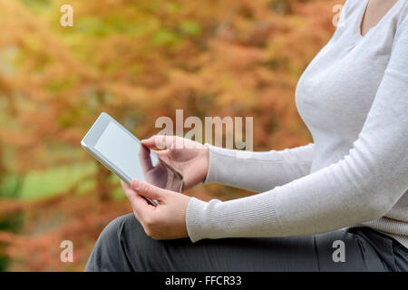 Woman holding a tablet PC in the autumn park Stock Photo