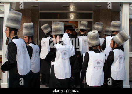 A group of Orthodox Jewish boys in fancy dress collecting for charity visit a wealthy man of the area; some houses are so popular they have a bouncer on the front door. Purim is one of the most entertaining Jewish holidays.  It commemorates the time when the Jewish people living in Persia were saved from extermination from a massacre by Haman. Due to the courage of a young Jewish woman called Esther. It is customary to hold carnival-like celebrations on Purim, and for groups of men to go round on the back of lorries and in open top buses visiting local wealthy men, collecting for their charity Stock Photo