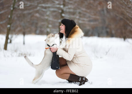 Woman with a gentle husky puppy in winter forest Stock Photo