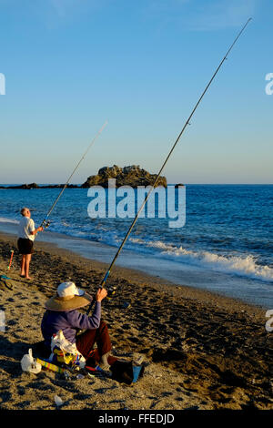 Two anglers fishing from the beach as the sun is going down. Almuñécar, Granada Province, Andalusia. Spain Stock Photo