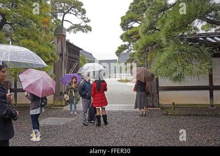 People on a tour of the Imperial Palace, Kyoto, Japan, in the rain Stock Photo