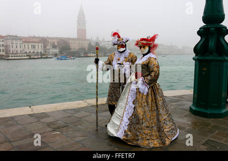 Maskierte Personen zum Karneval, im Hintergrund der Markusplatz mit Markusturm, Venedig, Italien. Stock Photo