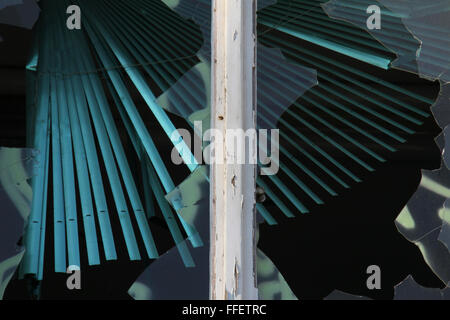 View on a broken window with glass shards and turquoise shutters Stock Photo