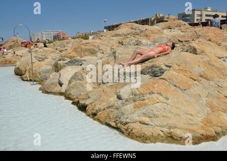 Woman sunbathing on rocks in a complex of swimming pools on the beach of Leca da Palmeira, Matosinhos, Portugal. Stock Photo