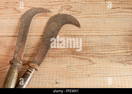 Two dated and used billhooks on wooden background Stock Photo