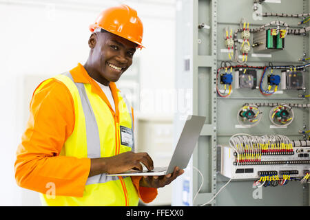 successful African electrical engineer using laptop checking machine status Stock Photo