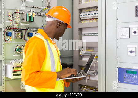 African American industrial engineer checking computerized machine status with laptop computer Stock Photo