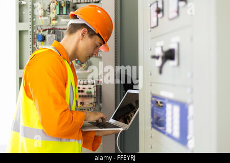 experienced electrician working in power plant control room Stock Photo