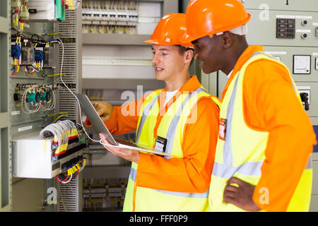 engineers checking distribution box with laptop in control room Stock Photo