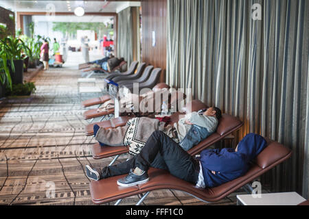 Exhausted,passengers,sleeping,sleep,deprived,lack of sleep,rest,on,lounge,chairs,beds,provided,at,departure,terminal,Changi Airport,Singapore,Asia, Stock Photo