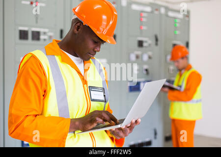 black technical worker using laptop with colleague on background Stock Photo
