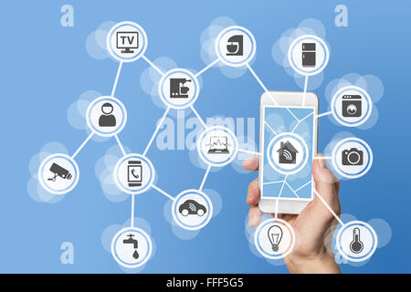 Home automation concept with hand holding modern smart phone to control home devices like a smart thermostat Stock Photo