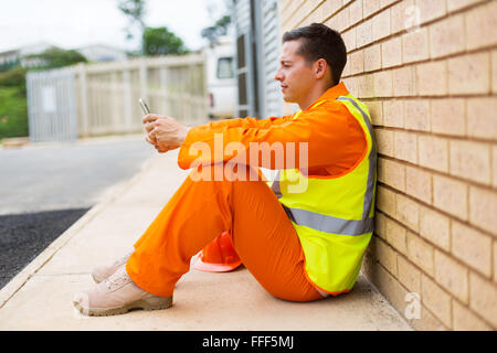 relaxed electrician using smart phone during break Stock Photo