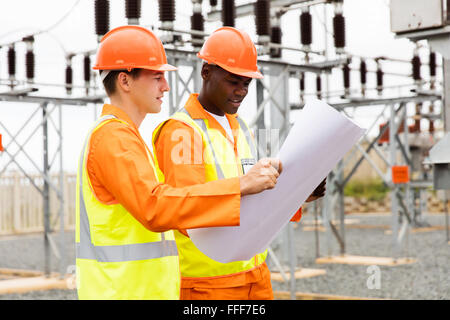 electric engineers discussing blueprint in substation Stock Photo