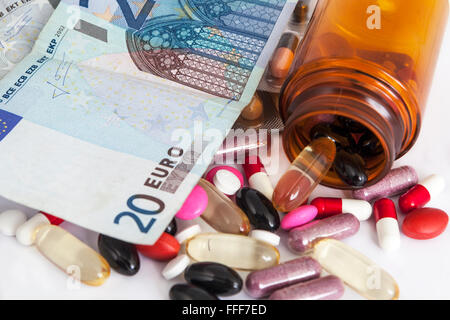 Open bottle of pills on a pile of money Stock Photo