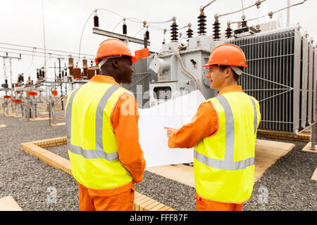 rear view of power company electrician working together in electrical substation Stock Photo