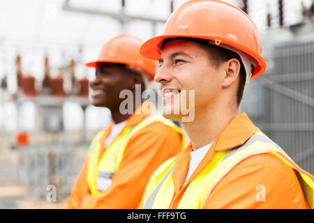 handsome electrical engineer looking away with colleague on background Stock Photo