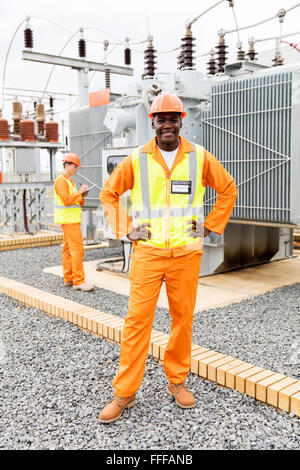 African American electrical technician with colleague on background in substation Stock Photo