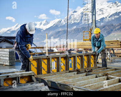 Construction workers lifting shuttering wall with crane, preparing framed formwork, Innsbruck Land, Tyrol, Austria Stock Photo