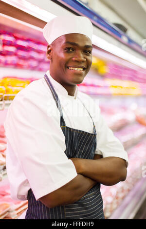 handsome African butcher with arms crossed in butchery Stock Photo