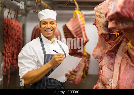butcher counting stock of beef hanging in cold room Stock Photo