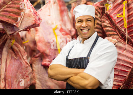 confident smiling middle aged butcher standing in cold room Stock Photo