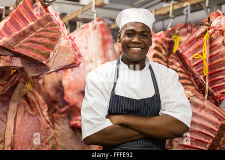 smiling African butcher standing in meat storeroom Stock Photo