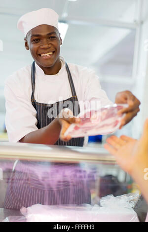 African butcher selling packed meat to customer in butchery Stock Photo