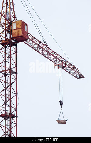 Tower crane carries load in bucket gas cylinders for cutting and welding. Stock Photo